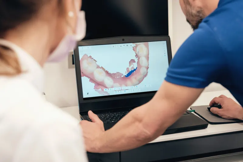 Dentist and technician reviewing a digital arch scan on a laptop