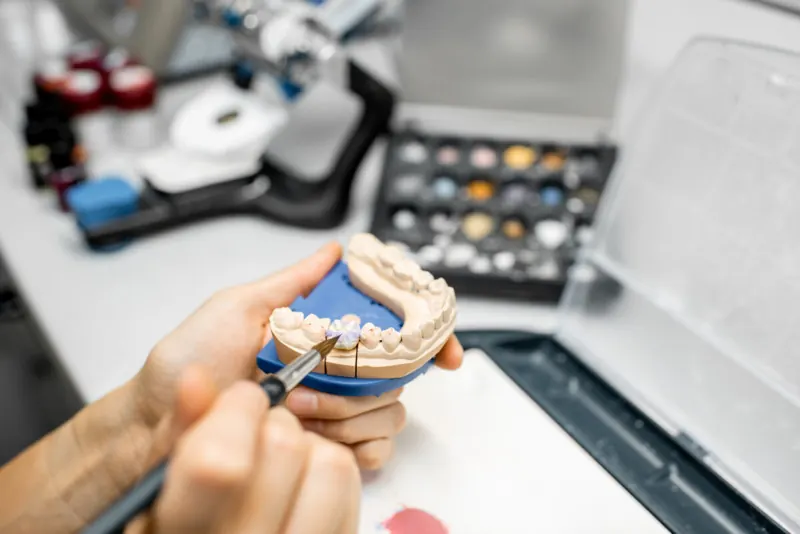 Technician applying custom shade to a ceramic restoration on a model